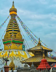 A vibrant daytime shot of the Swayambhunath Stupa (Monkey Temple) in Kathmandu, Nepal, featuring its iconic golden spire painted with the watchful eyes of the Buddha