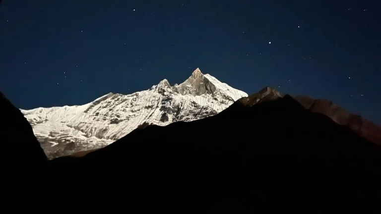 Snow-capped Himalayan mountain peak Machhapuchhre (Fishtail) under a starry night sky in Nepal.